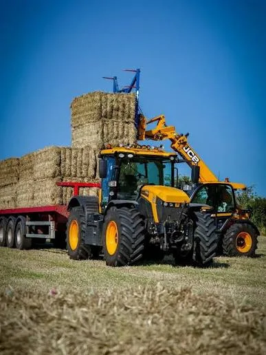 JCB loader stacking hay bales onto a trailer