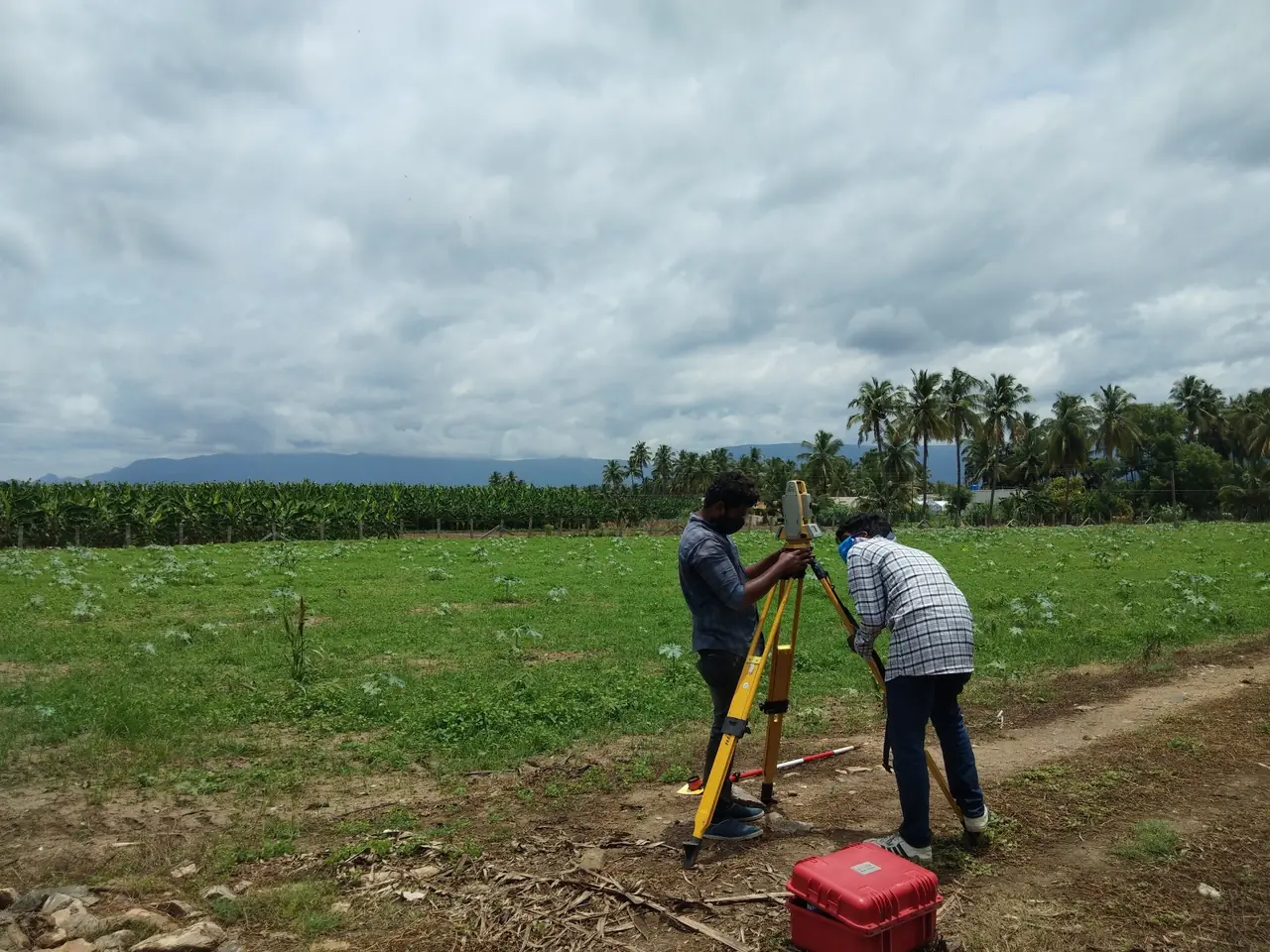 Surveyor using a theodolite in a green field